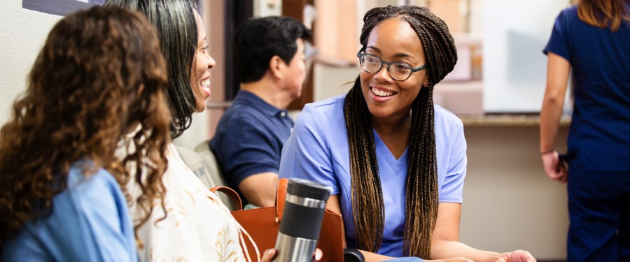 Female patients talk to female doctor in waiting room Female patients talk to female doctor in waiting room