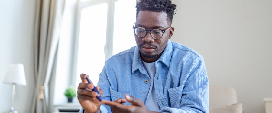 Diabetic Black man in glasses checks his blood sugar levels