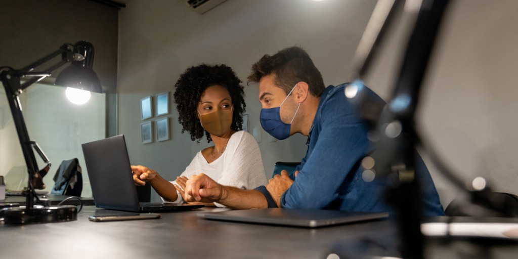 Business partners working together at the office wearing facemasks.