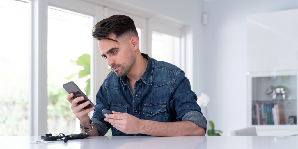 College student checking smartphone app for diabetes control. College student checking smartphone app for diabetes control.