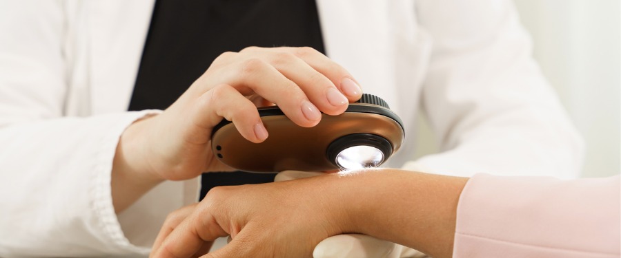 Woman getting hand examined for Skin Cancer Awareness Month