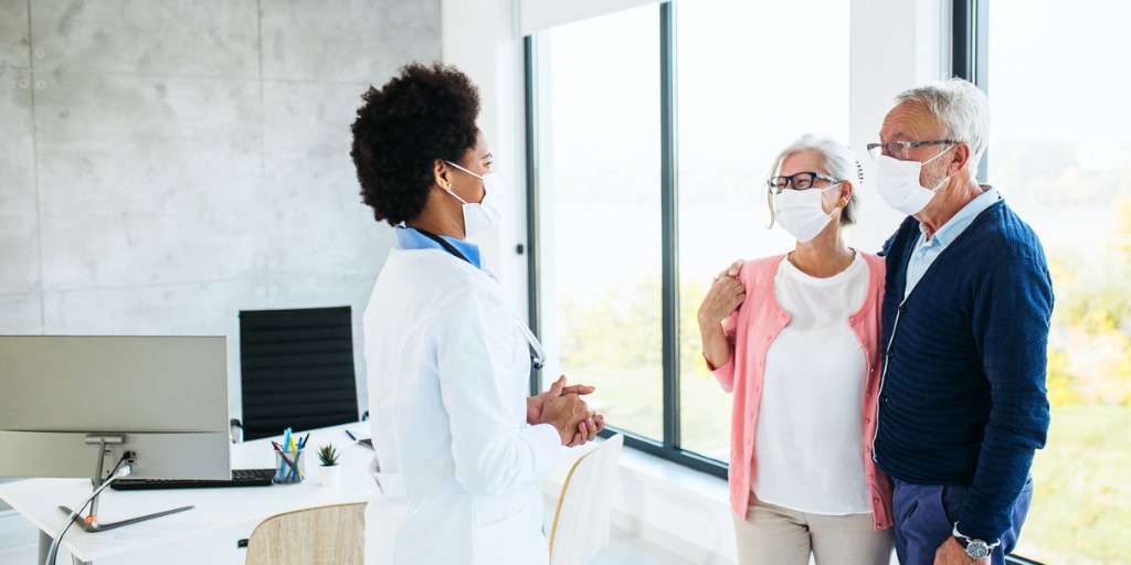 Female doctor speaking with senior patients in a modern office