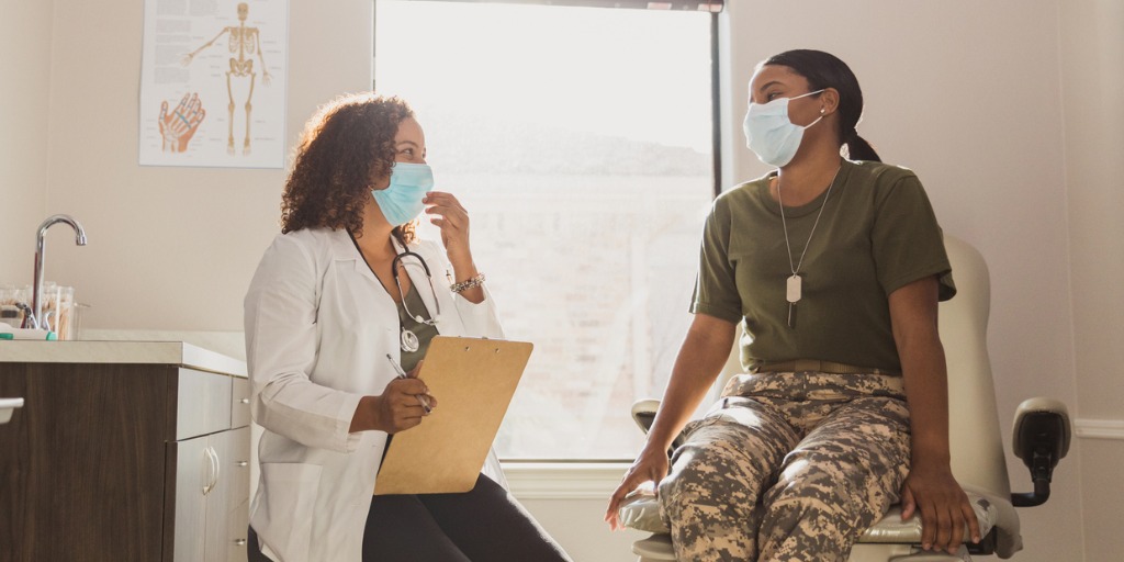 The mid adult female army soldier wears a protective mask when she goes to see her doctor in person during the coronavirus epidemic.