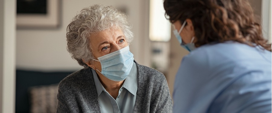 Woman wearing mask learning about Parkinson's disease from nurse Woman wearing mask learning about Parkinson's disease from nurse