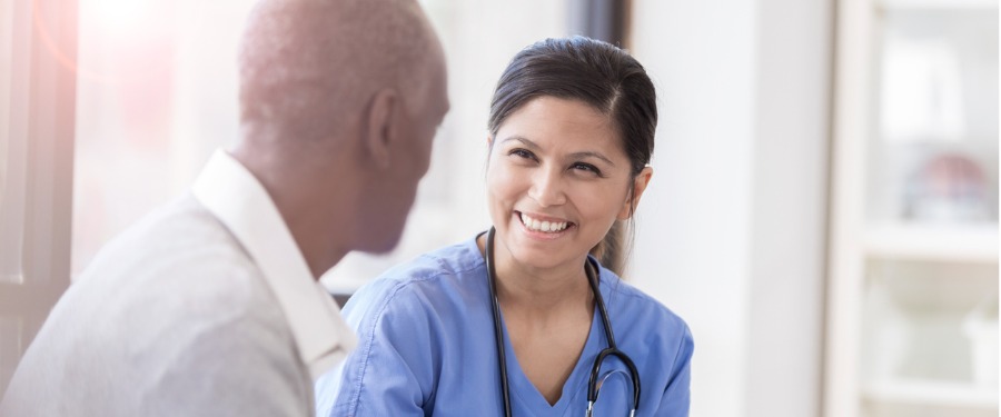 Female nurse discusses clinical trial with an older Black man