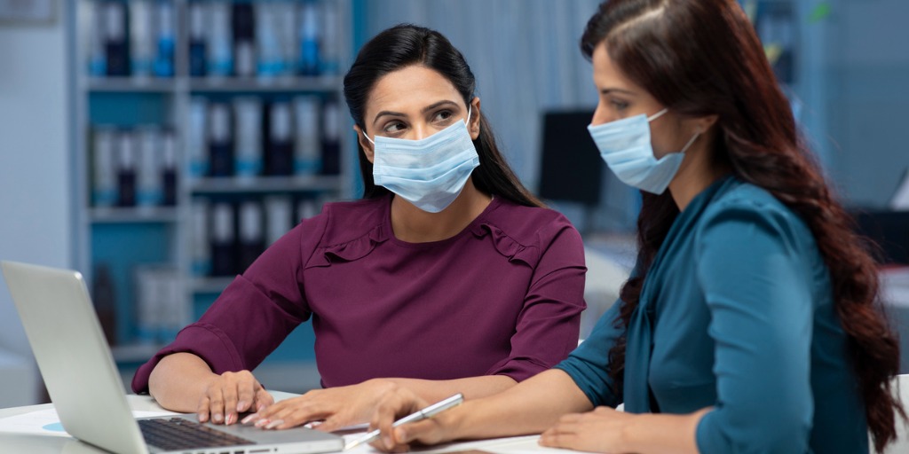 Two female employees discussing ideas at a work desk.