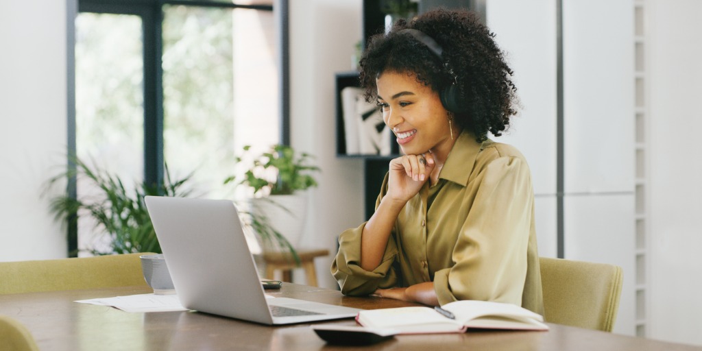 Shot of a young woman wearing headphones while using a laptop at home