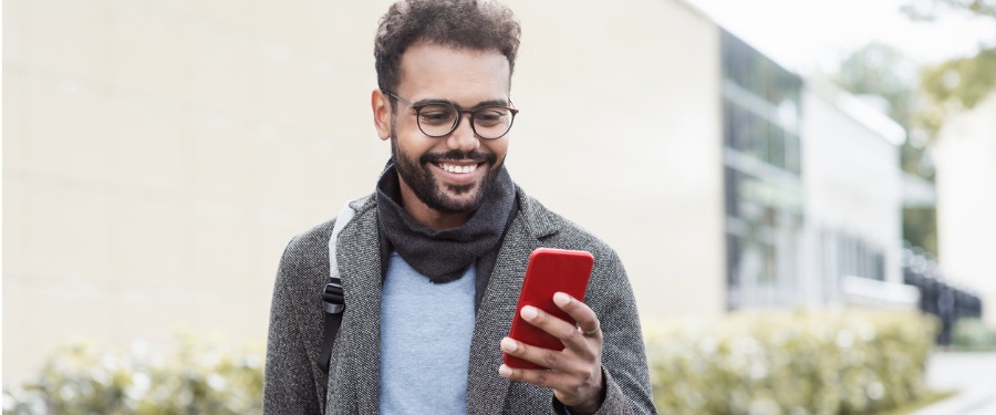 Man in blazer and glasses uses a smartphone
