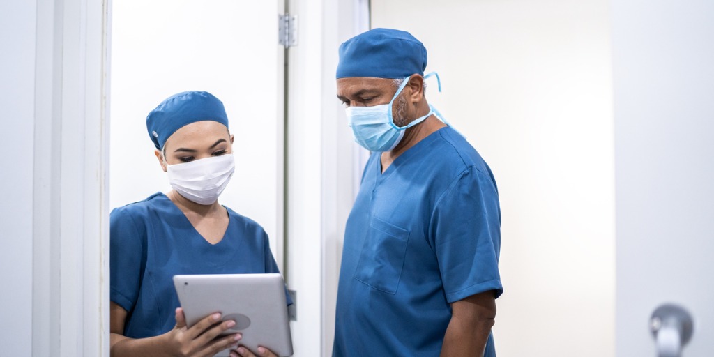 Healthcare coworkers walking and analyzing digital tablet at hospital
