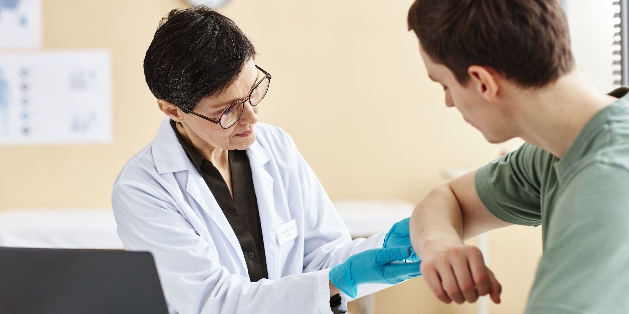female doctor checking male patient's arm for melanoma