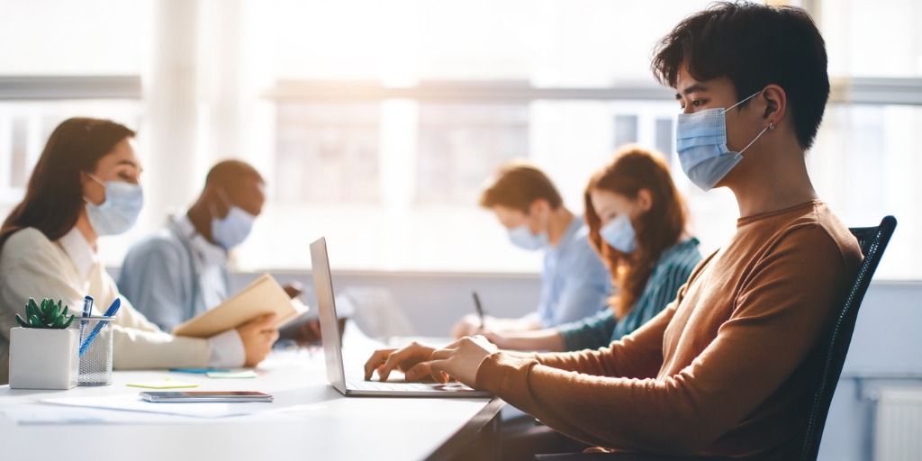 Group of employees wearing protective masks working in an open office. Group of employees wearing protective masks working in an open office.