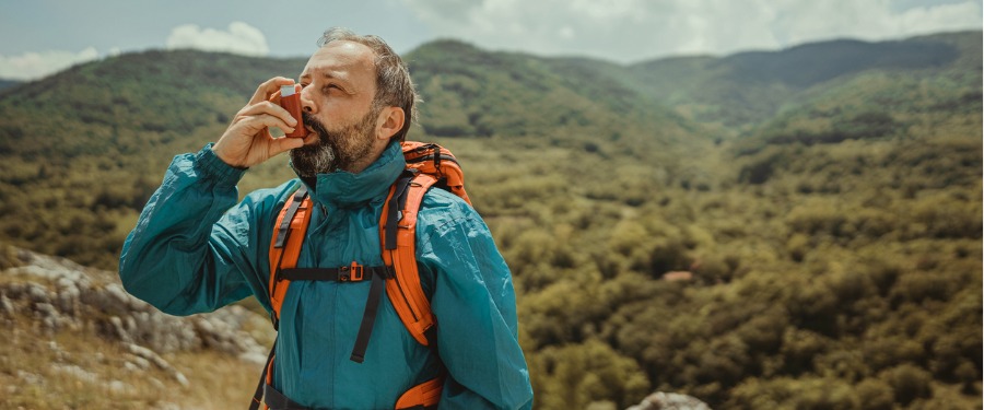 Man hiking and using asthma inhaler
