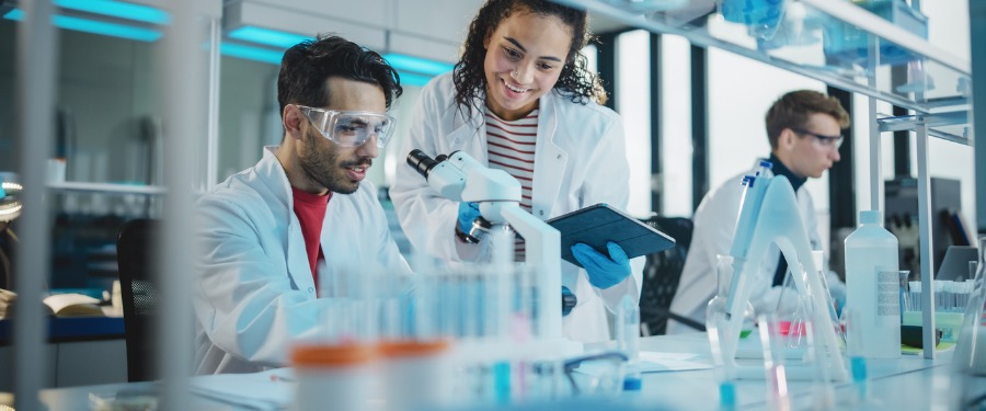 Two lab researchers looking at a microscope Two lab researchers looking at a microscope