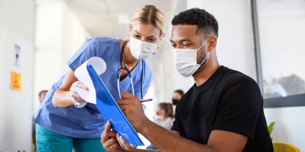 Portrait of nurse and man with face masks, coronavirus, covid-19 and vaccination concept, signing.