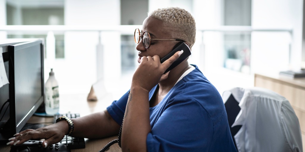 secretary-talking-on-telephone-at-hospital-reception-picture-id1197649993