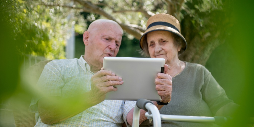 Senior couple using a digital tablet outside.