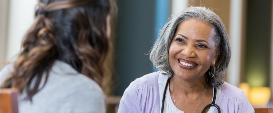 Smiling woman discusses clinical trial site support with second woman Smiling woman discusses clinical trial site support with second woman