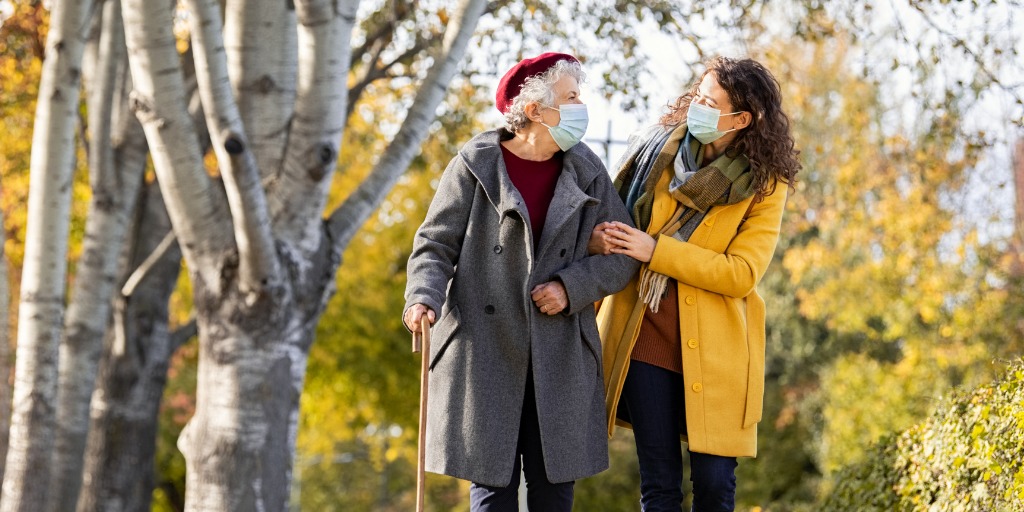 Mature woman with caregiver enjoying a walk on a sunny day. 