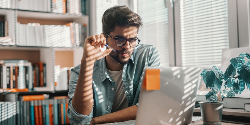 Man looking at laptop screen in office Man looking at laptop screen in office