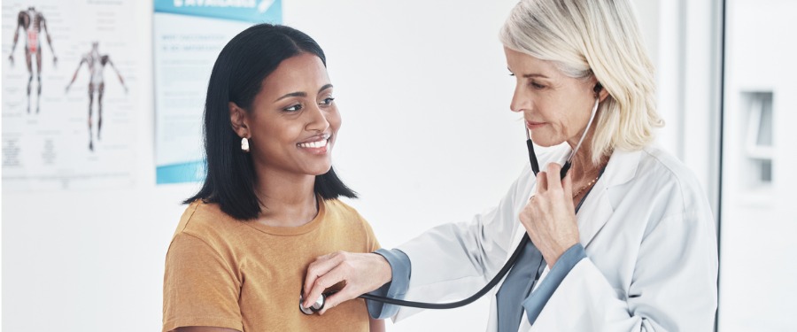 Female doctor listens to female patient’s lungs