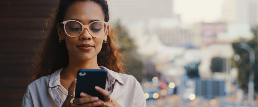 Woman downloading healthtech app to phone while standing outside