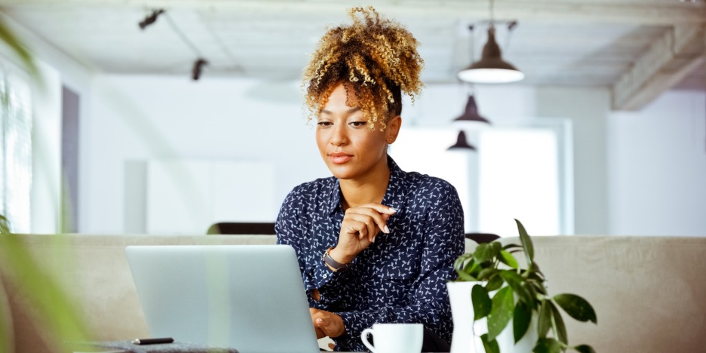 Female worker looking at laptop in office. Business executive is with confident look on her face.