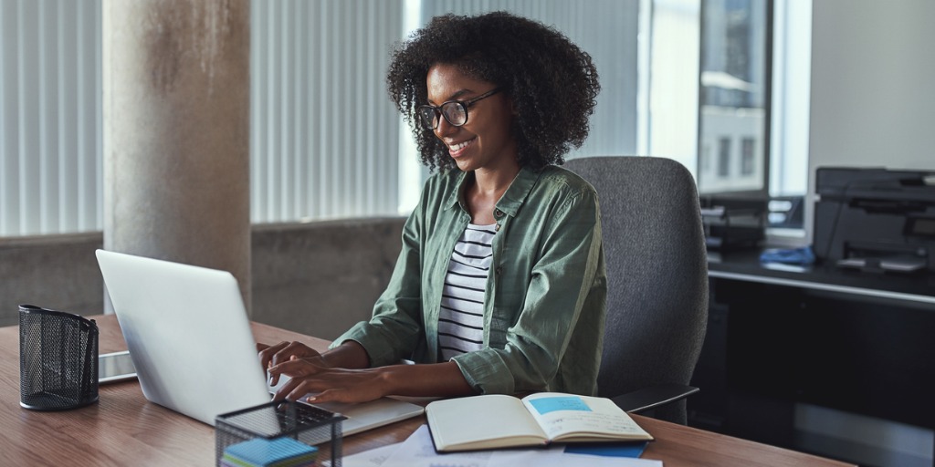 Portrait of a young creative businesswoman using laptop at her workplace in the modern office Portrait of a young creative businesswoman using laptop at her workplace in the modern office