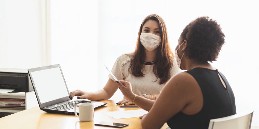 Two female colleagues looking at a laptop in a conference room. 