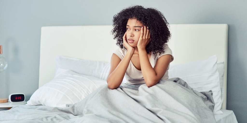 Young woman suffering from fatigue laying in her bed.