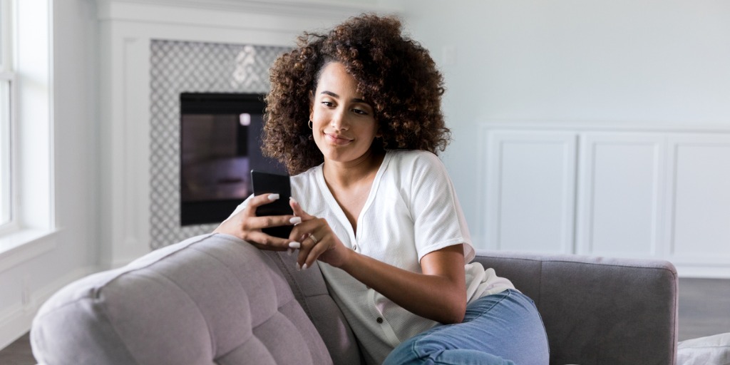 Woman using smartphone on sofa Woman using smartphone on sofa