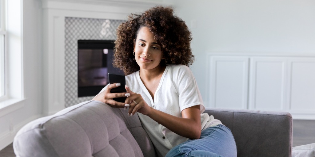 Woman using smartphone on sofa