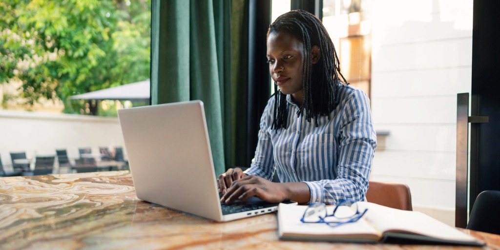 Young woman working on her laptop in an outdoor office setting.