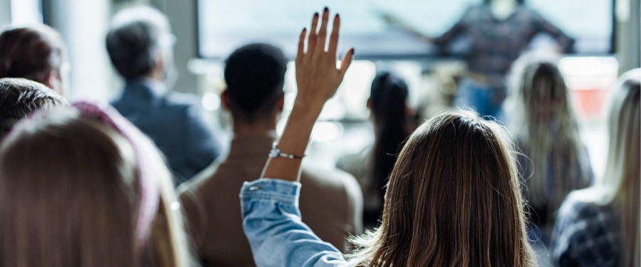 Woman asking a question during a clinical trial recruitment company presentation