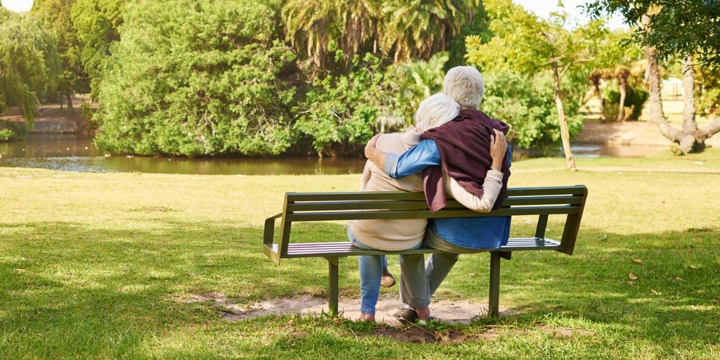 MS patient sitting on a bench with a care partner